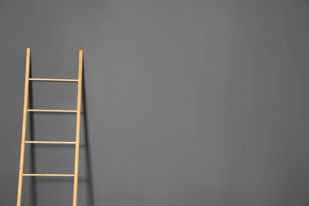 Modern wooden ladder on grey background. Space for text - Foto, imagen