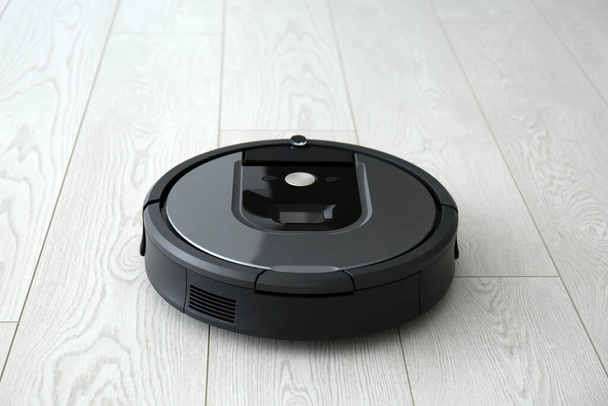 Modern robotic vacuum cleaner on wooden floor - Фото, изображение