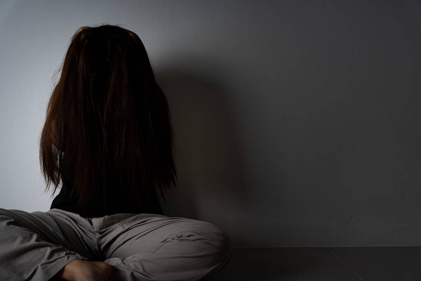 mujer triste abrazar su rodilla y llorar sentado solo en una habitación oscura. Depresión, infeliz, estresado y trastorno de ansiedad concepto
. - Foto, Imagen