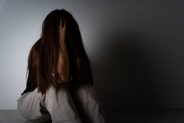 mujer triste abrazar su rodilla y llorar sentado solo en una habitación oscura. Depresión, infeliz, estresado y trastorno de ansiedad concepto
. - Foto, imagen
