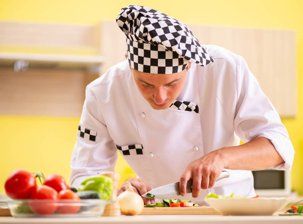 Jovem cozinheiro profissional preparando salada na cozinha - Foto, Imagem