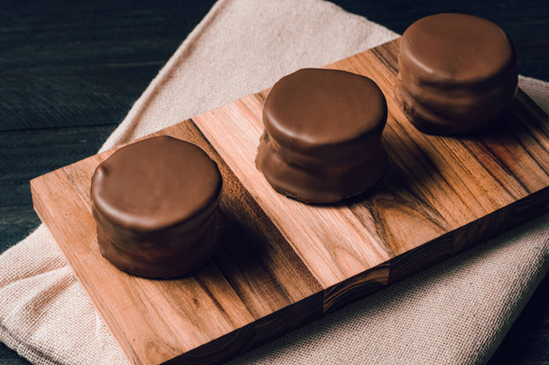 テーブルクロスの上に黒テーブルの上に伝統的な甘いアルゼンチンのチョコレートビスケット - 写真・画像