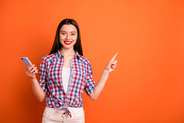Portrait of positive confident cool girl cute promoter search ads indicate promotion point index finger wear white pants trousers good looking outfit isolated over orange color background - Valokuva, kuva