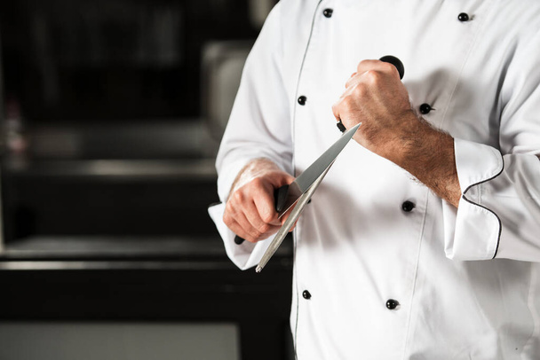 Keittiöravintolan keittiömestari veitsen kanssa. Lähikuva kokki kädet veitsellä. - Valokuva, kuva