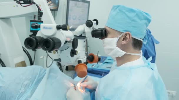 Egy sebész vizsgálja a mikroszkópot a női páciens szemén a műtőben. Orvos mikroszkóppal a szemműtét során, szürkehályog kezelése és dioptriás korrekció. - Felvétel, videó
