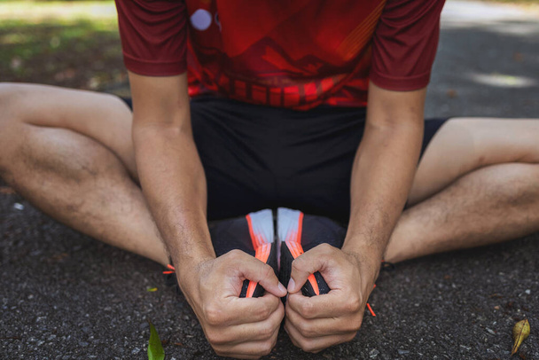 urheilija juoksija lämmittää ruumiinsa ennen kuin alkaa ajaa tien päällä puistossa pehmeällä tarkennuksella ja taustalla valolla - Valokuva, kuva