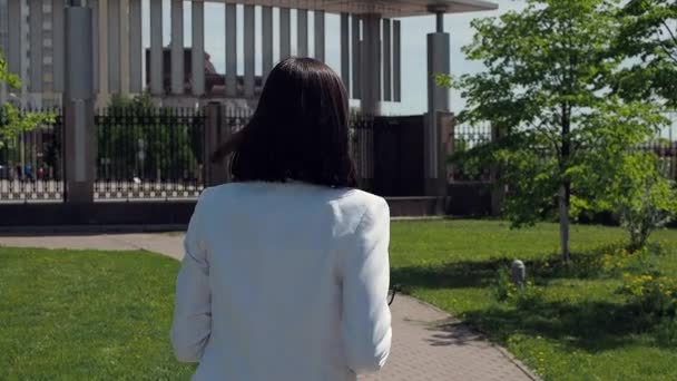 Tyylikäs nainen kävelee polulla puistossa - Materiaali, video