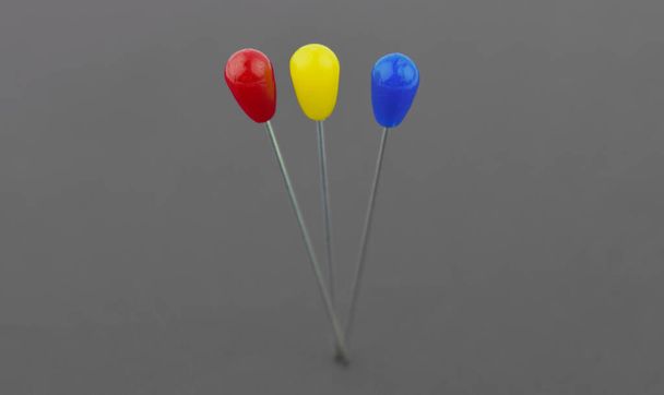 Drie verschillende gekleurde broches pin naast elkaar geplaatst op een papieren achtergrond - Foto, afbeelding