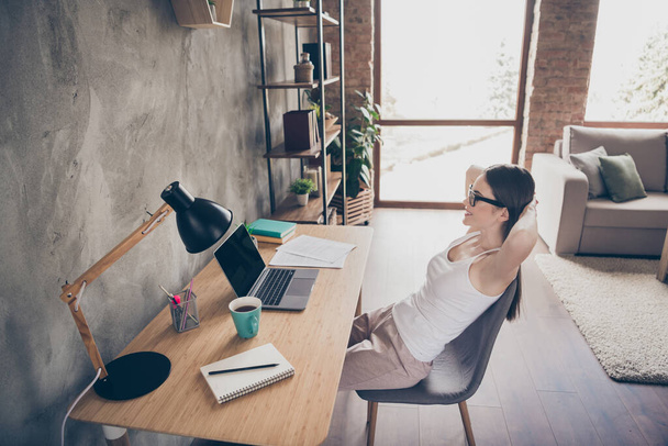 Profile side photo of positive cheerful satisfied girl ceo lawyer work remote quarantine relax watch laptop interesting serious project complete stretch hands sit desk chair in house indoors - 写真・画像