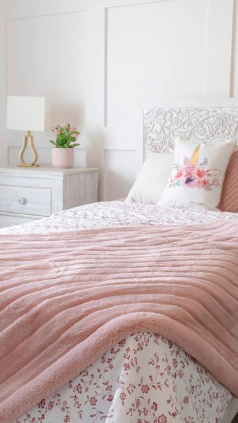 Vertikale Schlafzimmerausstattung mit femininen floralen Bettwäschen und dekorativem Kopfteil auf dem Bett - Foto, Bild