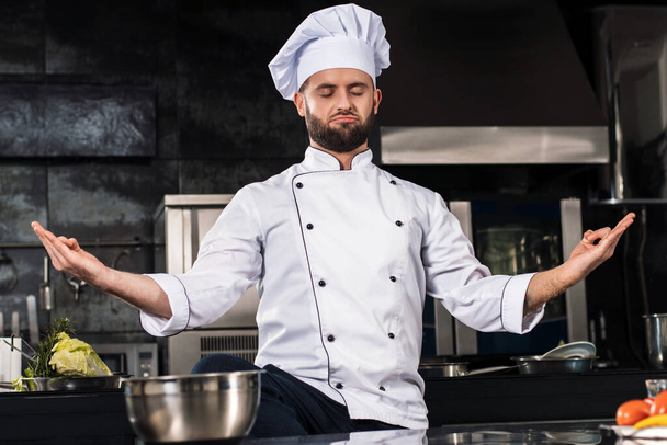 Chef man posing at professional kitchen. Chef in meditation pose. - Fotografie, Obrázek