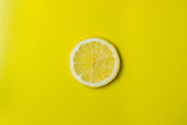 Una rodaja de limón se encuentra sobre un fondo amarillo. Rebanada redonda de limón. Foto arriba
 - Foto, Imagen