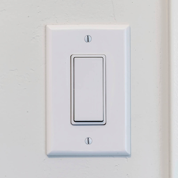 Quadro quadrado Interruptor elétrico da luz do balancim com alavanca larga lisa na parede interior branca
 - Foto, Imagem