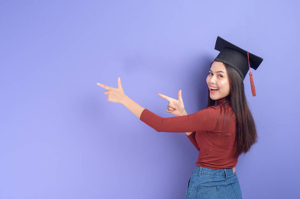 Portrait of young University student woman with graduation cap on violet background  - Valokuva, kuva