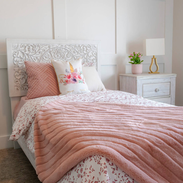 Quadratische Schlafzimmerausstattung mit dekorativem Kopfteil und femininen Bettwäsche auf Einzelbett - Foto, Bild