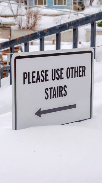Estrutura vertical Escadas enterradas na neve de inverno com sinal que diz: Por favor, use outras escadas
 - Foto, Imagem