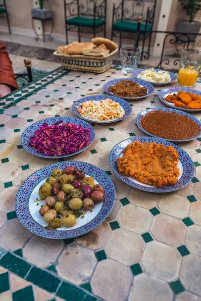 Una selección de mezze o aperitivos marroquíes que incluyen zanahorias, papas y remolacha, en platos azules y blancos individuales en un restaurante en Fez, Marruecos
. - Foto, Imagen