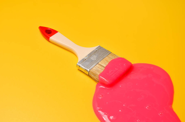Shot of a brush with pink sticky slime on yellow background. Minimalism in photography, concept creative picture. Painting tool - Foto, Imagen