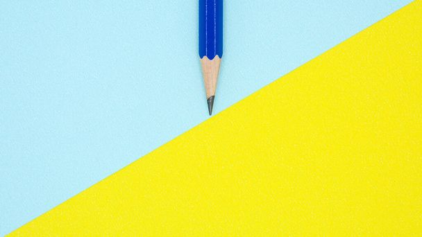 blue pencil on blue and yellow paper - background - Photo, Image