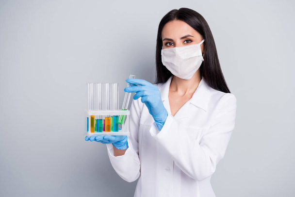 Close-up portrait of her she nice attractive girl biologist scientist expert doc holding in hands flasks analyzing creating remedy cure meds medical solution isolated over grey pastel color background - 写真・画像