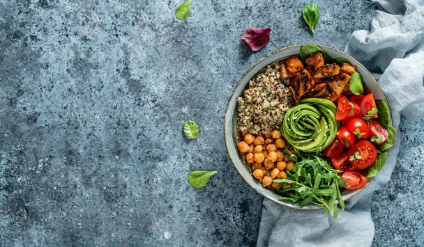 Buddha bowl salad with baked sweet potatoes, chickpeas, quinoa, tomatoes, arugula, avocado, sprouts on light blue background with napkin. Healthy vegan food, clean eating, dieting, top view - Photo, Image