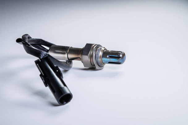 The oxygen sensor is a new lambda sensor. Spare parts on the car on a gray gradient background - Foto, immagini