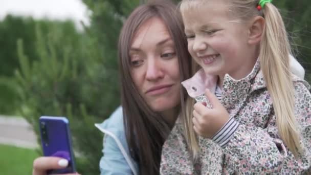 Venäläinen äiti, jolla on kaunis pieni tytär, ottaa selfien puhelimeensa kävellessään - Materiaali, video