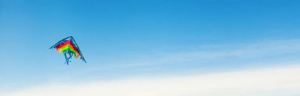 Banner com pipa colorida voando alto no céu azul
 - Foto, Imagem
