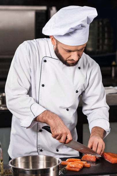 Chef männlich Lachs in Scheiben schneiden in Küche Restaurant. Chef in Uniform schneidet Fischfilet. - Foto, Bild