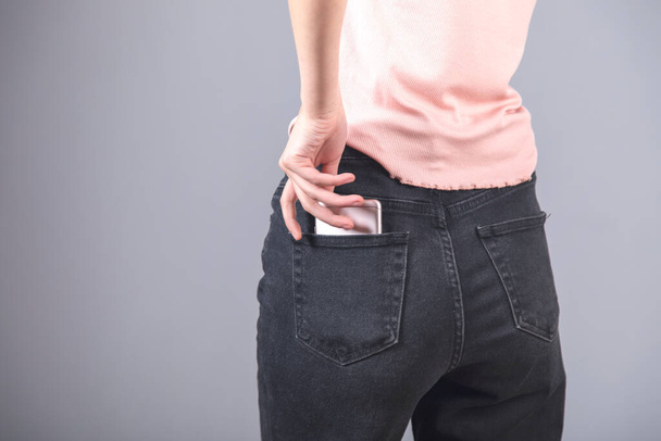 phone on woman jeans pocket on grey background - Fotó, kép
