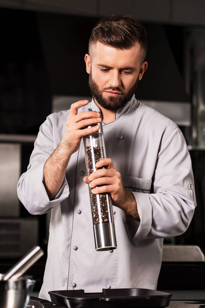 Chef with pepperbox at professional kitchen. Chef male with pepperbox. - Фото, изображение