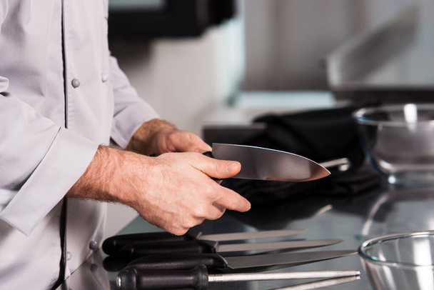 Chef hands with knife at kitchen restaurant. Closeup hands of male check knife. - Foto, Imagen