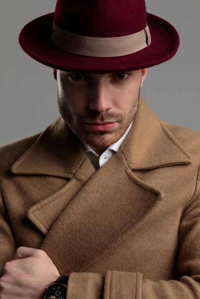misteriosa modelo joven con sombrero y abrigo largo sobre fondo gris
 - Foto, Imagen