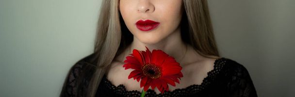 Portret van een meisje met een rode gerbera bloem. - Foto, afbeelding