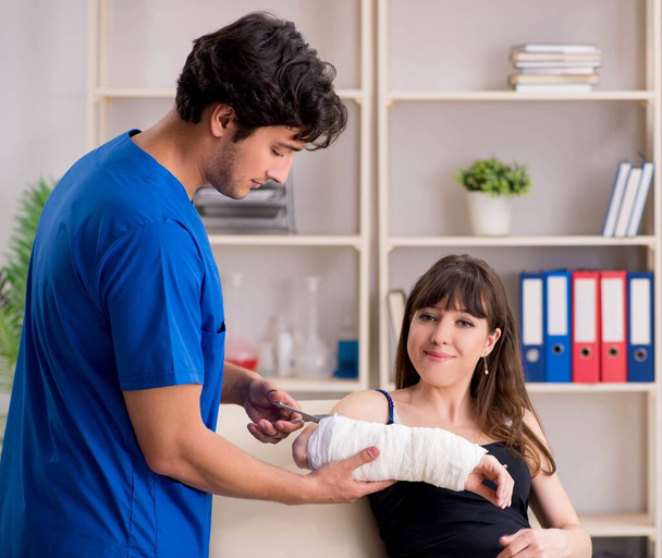 Young woman with bandaged arm visiting male doctor traumotologis - Photo, Image
