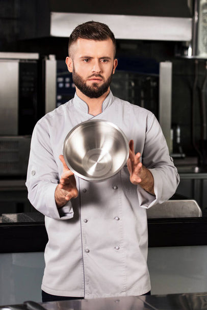 Chef hombre con tazón. Chef macho en uniforme mantener cuenco de acero en restaurante de cocina
. - Foto, imagen
