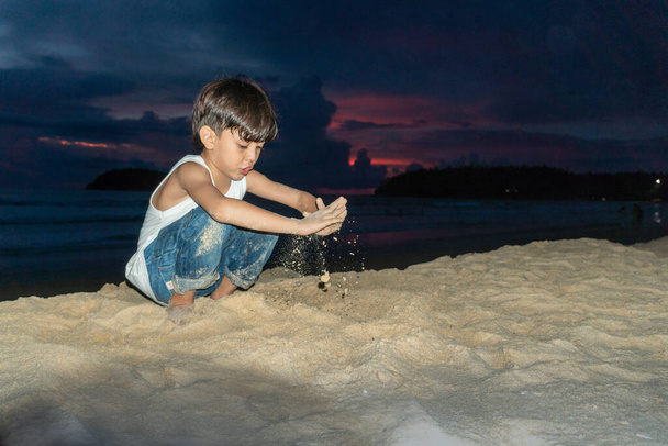 Ein Junge spielt Sand in der Dämmerung am Kata Strand Phuket Thailand - Foto, Bild