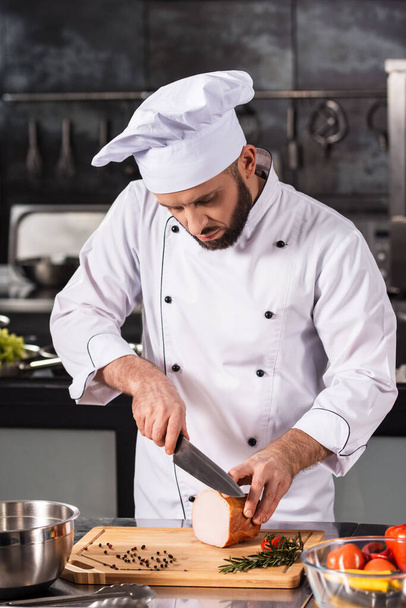 Chef schneidet Fleisch in der Küche. Chef männliche Scheibe brummt in professioneller Küche. - Foto, Bild