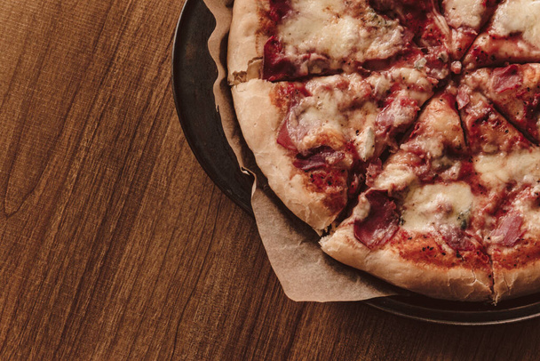 Pizza casera con mozzarella y jamón con albahaca. Sobre una mesa de madera
. - Foto, Imagen
