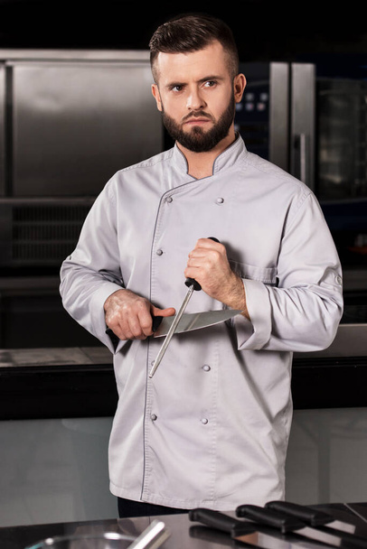 Mutfak restoranında bıçaklı aşçı. Erkek aşçı mutfakta keskin bıçak.. - Fotoğraf, Görsel