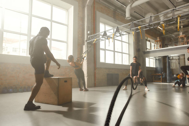 We make you fit. Full length shot of sportive people having workout at industrial gym. Group training, teamwork concept - Fotó, kép