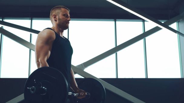 Athletic handsome male sportsman working in the gym using barbell. Strong and healthy bodybuilder abdominal training exercises. Sport, fitness, workout and lifestyle concept. - Φωτογραφία, εικόνα