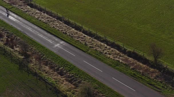 Imágenes del dron de una persona montando en bicicleta a lo largo de un camino rural vacío en una mañana soleada en Yorkshire del Norte Inglaterra completamente aislada
 - Metraje, vídeo