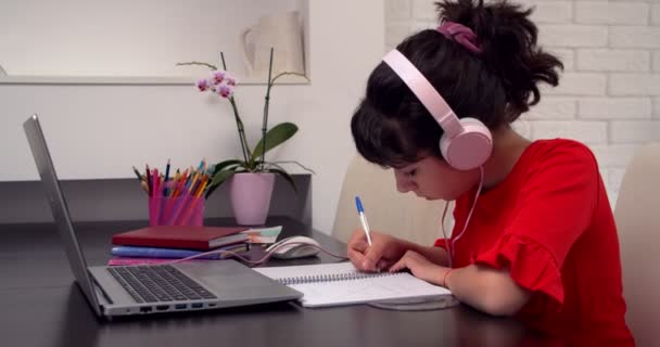 十代の女の子の学生は自宅でラップトップを使用してビデオチャットで教師とオンラインレッスンを勉強します。Eラーニングクラス、距離コース、およびコロナウイルス流行における教育の概念。4K - 映像、動画