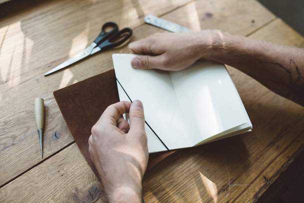  close up hands of a man working with notebook and brown leather on the  table - Photo, Image