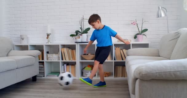 隔離COVID-19中に自宅でサッカーをしている6歳の少年。アパートでの生活スタイル。4k - 映像、動画