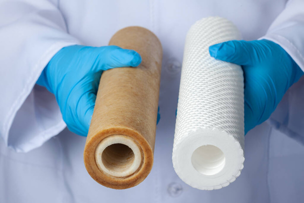 Cartuchos de filtro de agua nuevos vs usados en manos expertas del laboratorio. Concepto de tratamiento de agua
 - Foto, Imagen