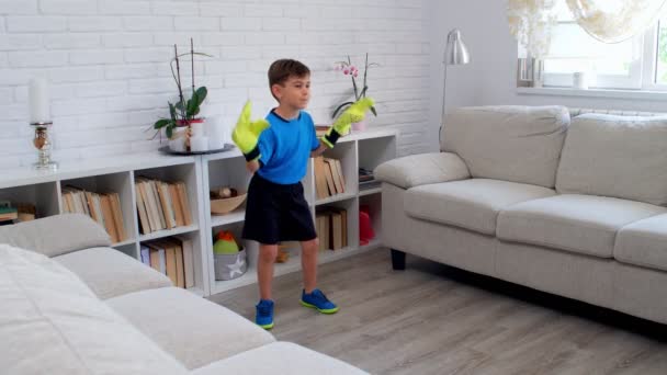 Un garçon de six ans jouant au football avec des gants de gardien à la maison pendant la quarantaine COVID-19. Piquet de vie dans l'appartement. 4k - Séquence, vidéo