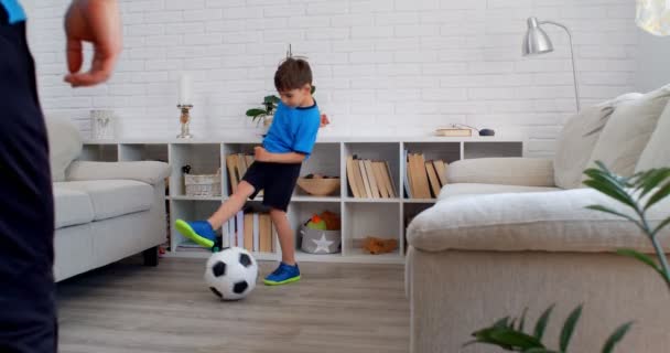 Een jongen van zes die thuis voetbal speelt tijdens quarantaine COVID-19. Levensstijl in het appartement. 4k - Video