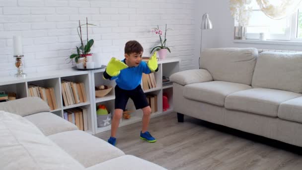 6歳の少年は、隔離されたCOVID-19中に自宅でゴールキーパーの手袋でサッカーをしています。アパートでの生活スタイル。4k - 映像、動画